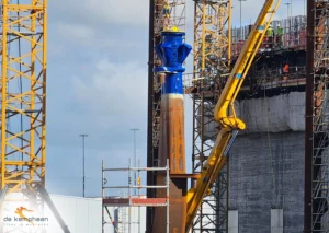 rote metalen buis 'J-TUBE5' voor offshore windmolenpark hangend aan hijskraan